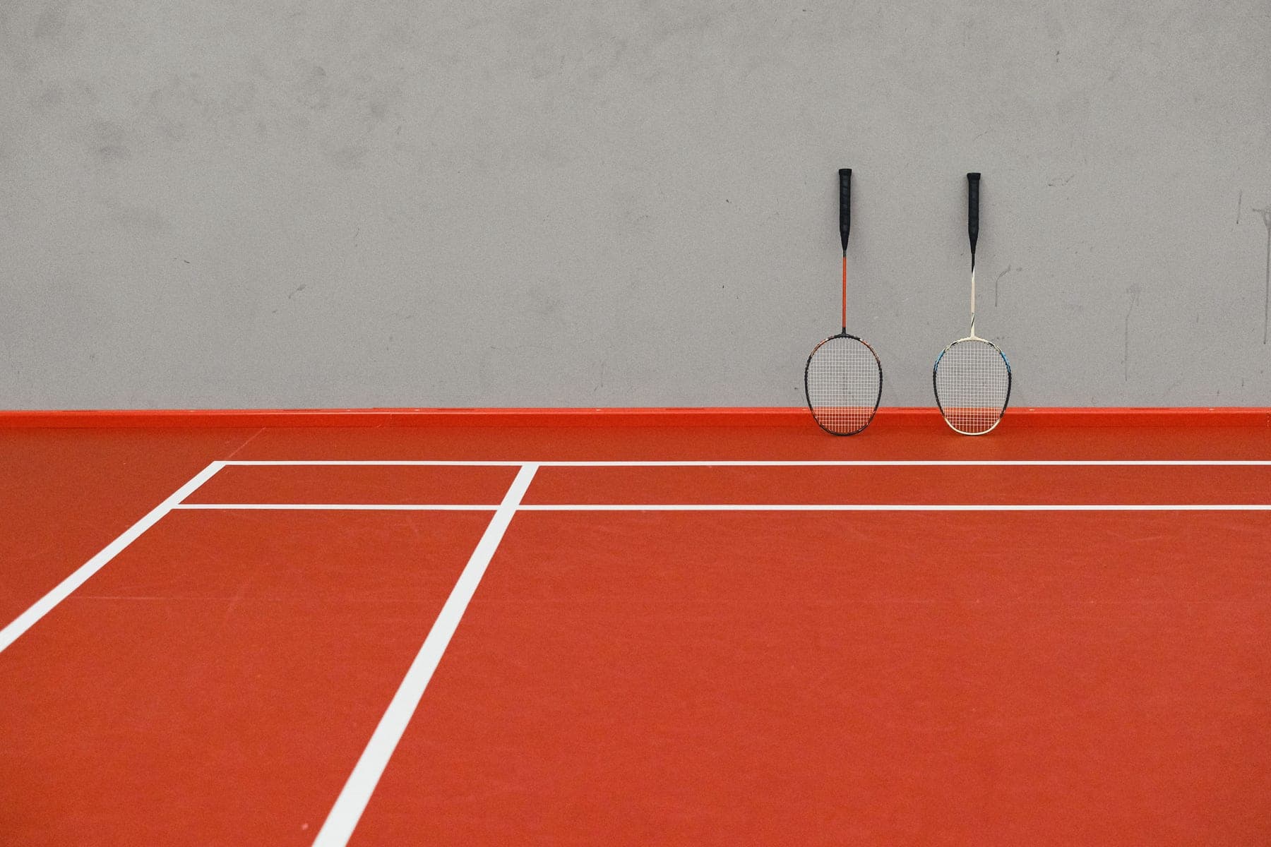 Tennis, padel and pickleball equipment arranged side by side on a court
