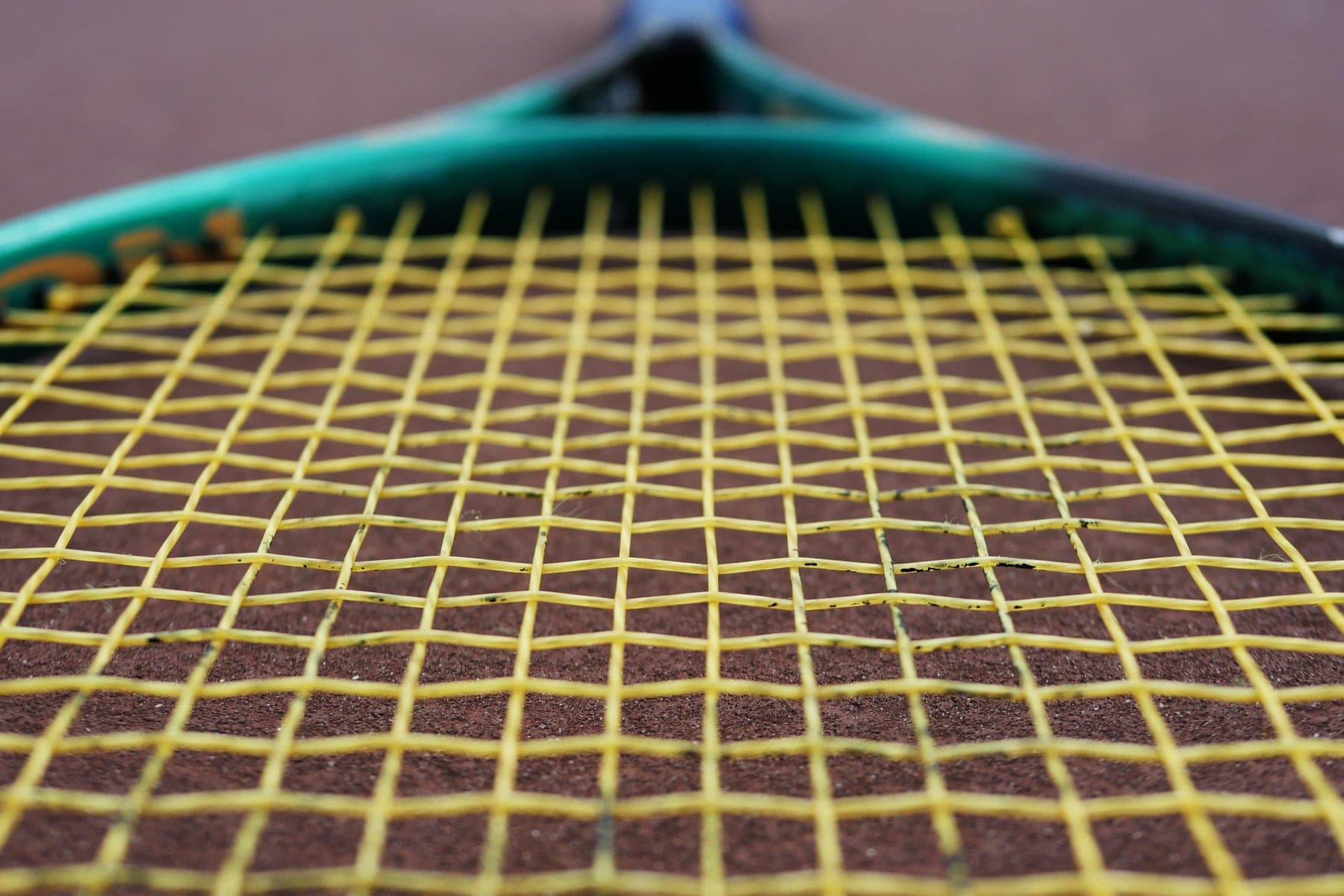 Tennis string bed, balls and an overgrip arranged on a court surface