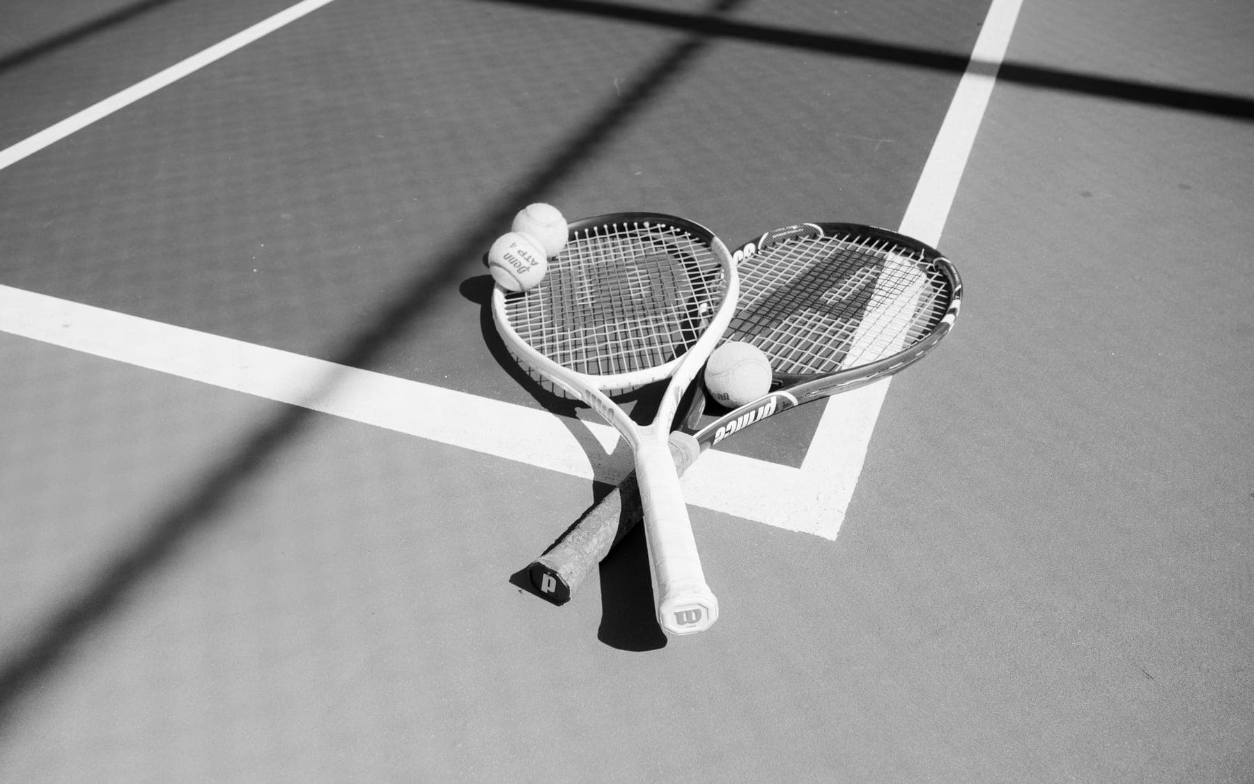 Tennis, padel and pickleball equipment arranged on a hard court surface